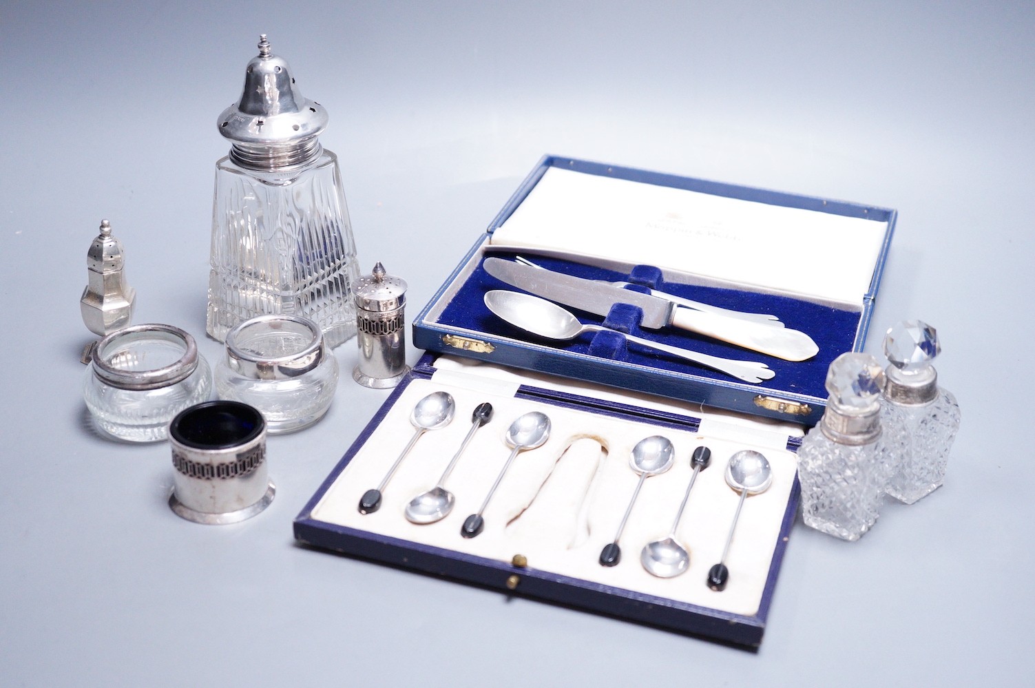 A modern 17th century style silver dog nose christening spoon and fork by Mappin & Webb, an associated knife, a cased set of six silver bean end coffee spoons (lacking tongs), a silver three piece condiment set and five